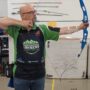 An archery coach shooting a bow and arrow.